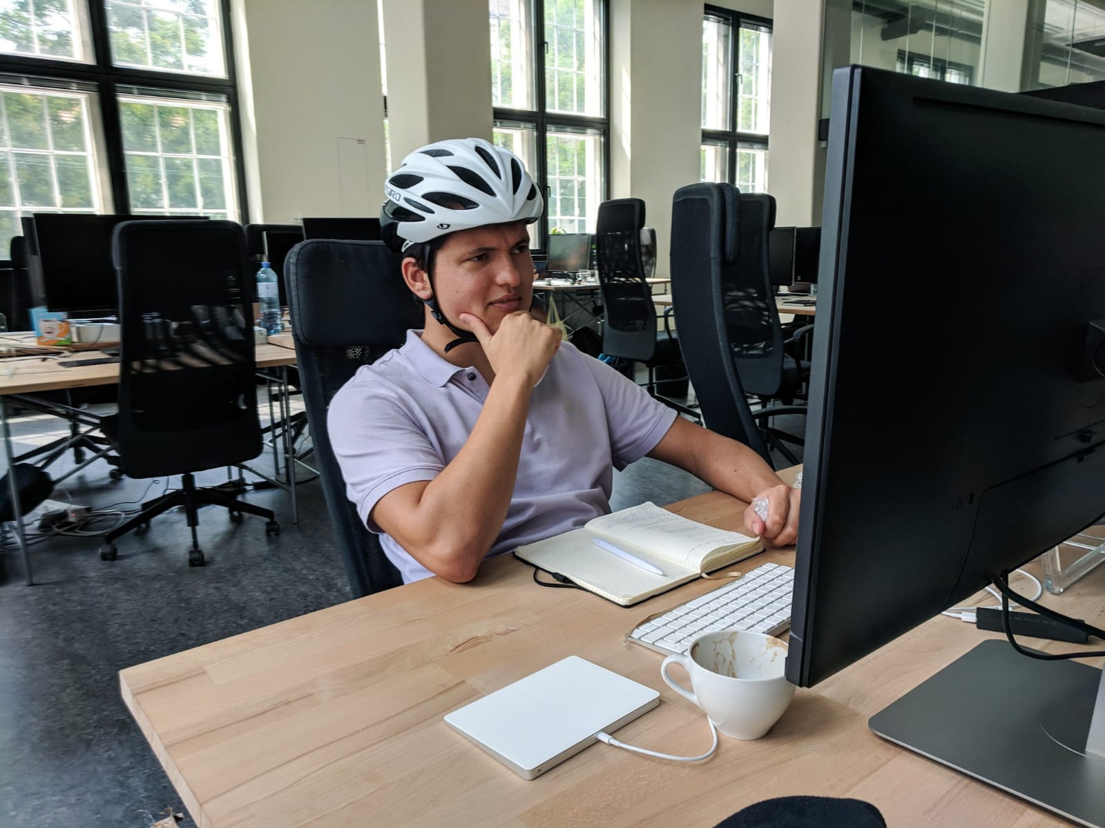 Lukas working at a computer while wearing a bicycle helmet