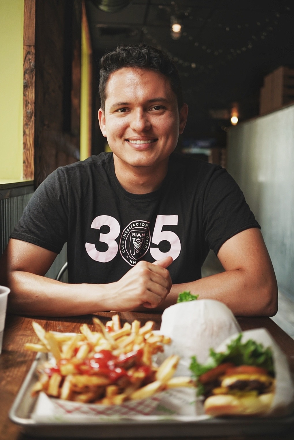 Lukas seated at a table with a burger