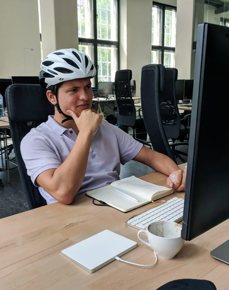 Lukas wearing a helmet while looking at a computer screen and in deep thought